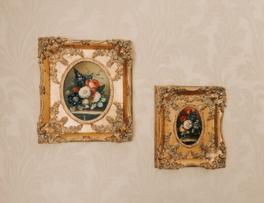 a pair of flower paintings in a gold frame posted on wall